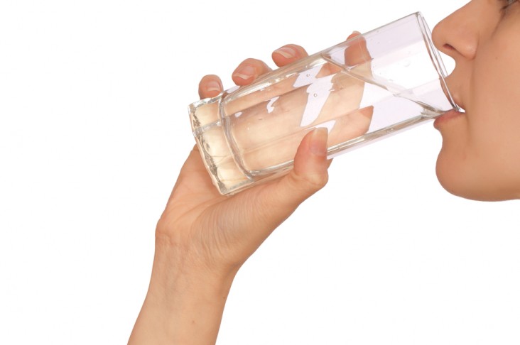 Woman drinking water from a glass to help prepare for a colonoscopy